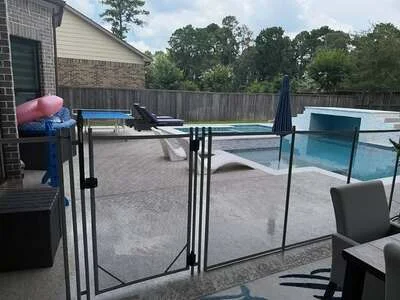 Black aluminum pool fence with gate surrounding in-ground pool area