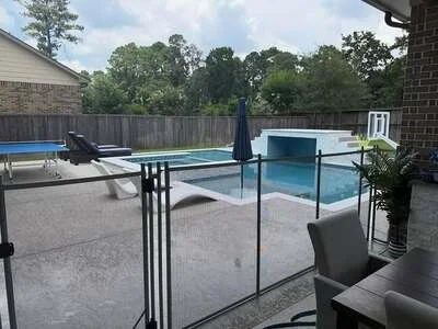 Frameless glass pool fence with black aluminum posts surrounding in-ground pool