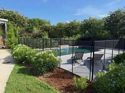 Black aluminum mesh pool safety fence with gate around in-ground pool