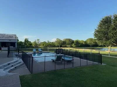 Black aluminum pool safety fence with gate around in-ground pool on manicured lawn